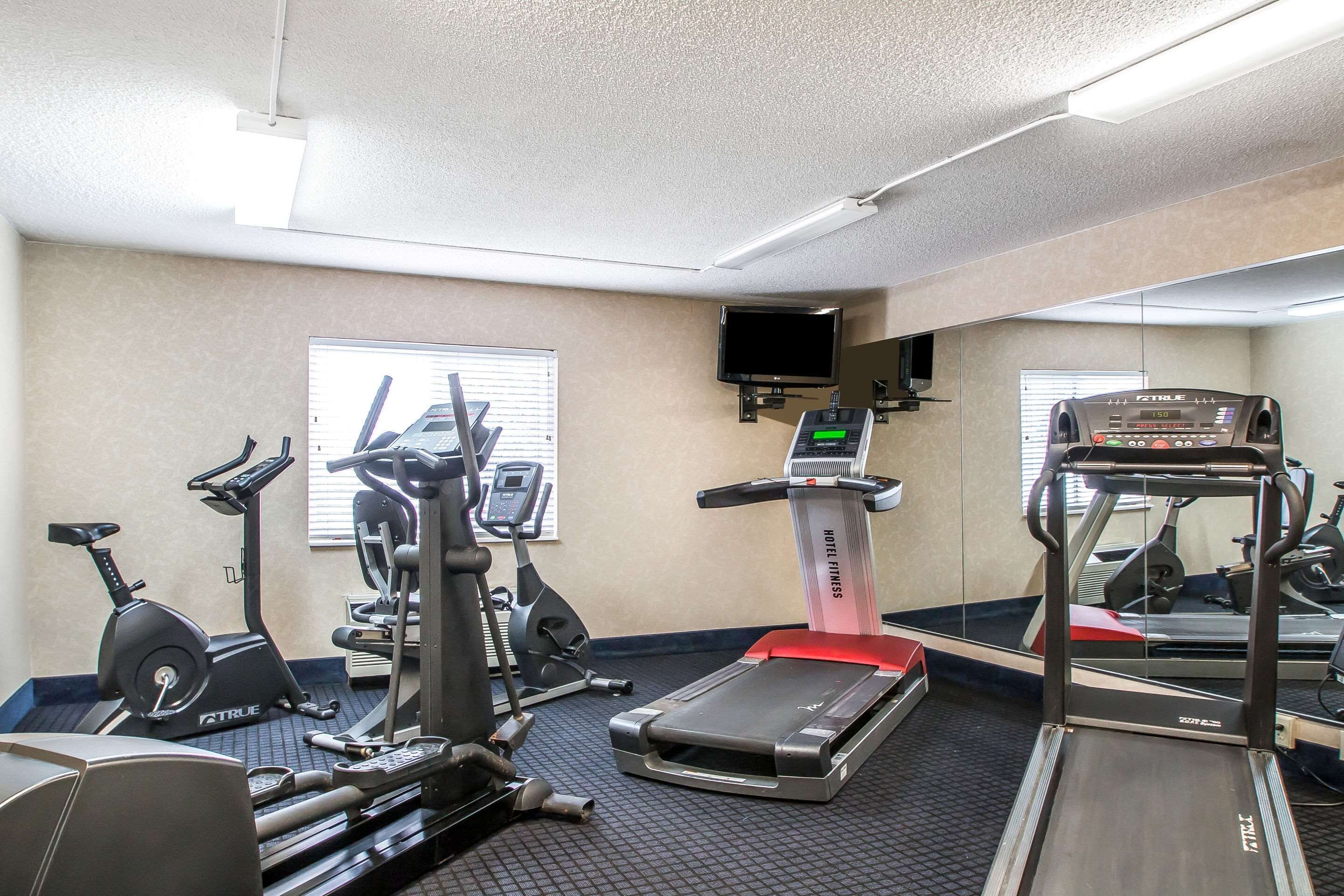 A gym with various exercise equipment including treadmills, stationary bikes, and elliptical machines.