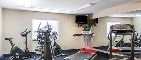 A gym with various exercise equipment including treadmills, stationary bikes, and elliptical machines.
