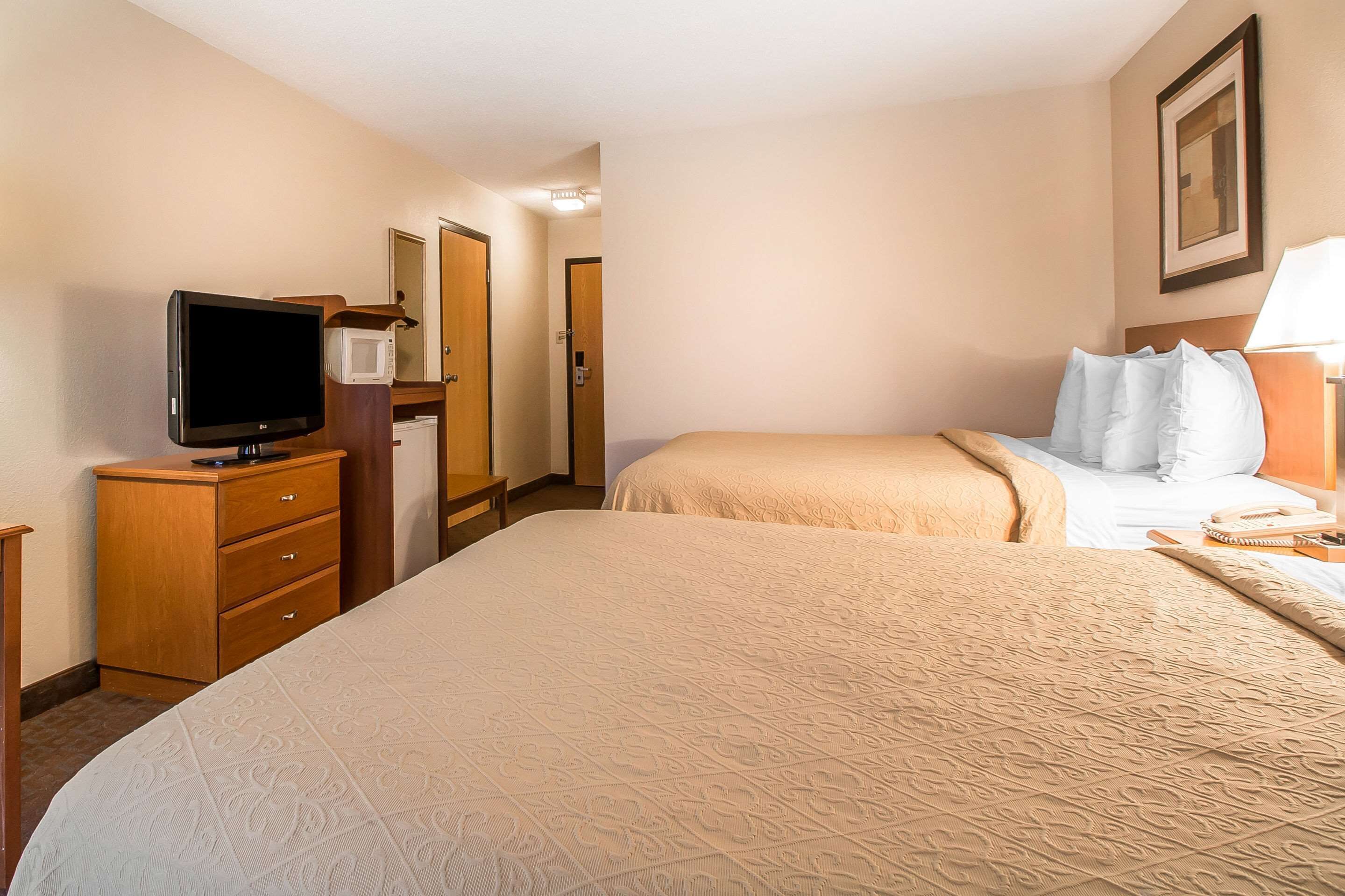 Une chambre d’hôtel avec un grand lit, une télévision, un four à micro-ondes et un bureau avec des tiroirs.