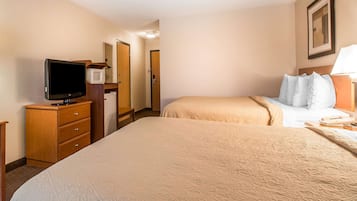 Une chambre d’hôtel avec un grand lit, une télévision, un four à micro-ondes et un bureau avec des tiroirs.