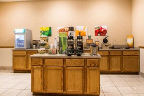 A hotel breakfast bar with a coffee machine, tea dispensers, and a waffle maker.