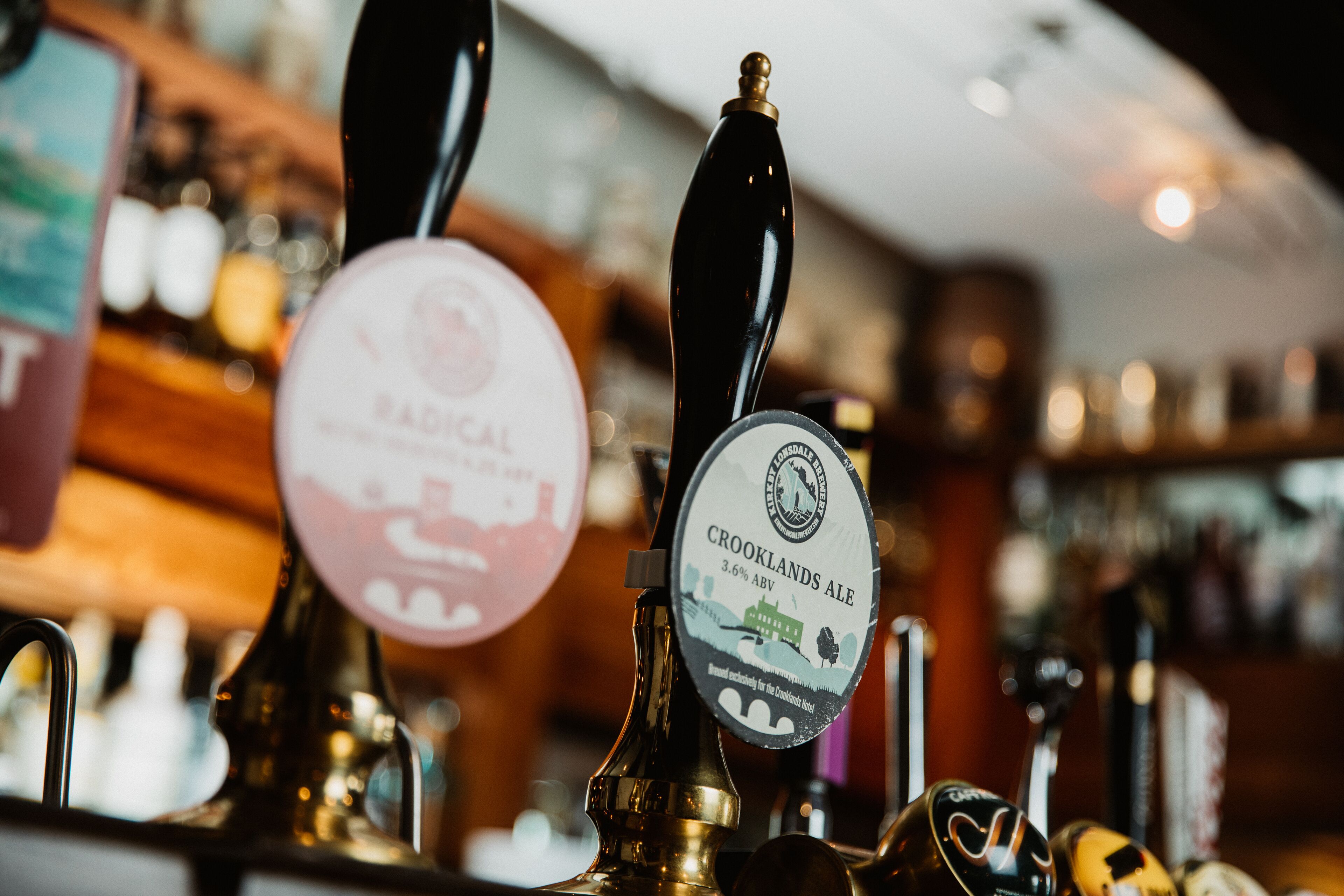 Eine Bar mit zwei Zapfhähnen, einer beschriftet mit 'RADICAL' und der andere mit 'CROOKLANDS ALE'.
