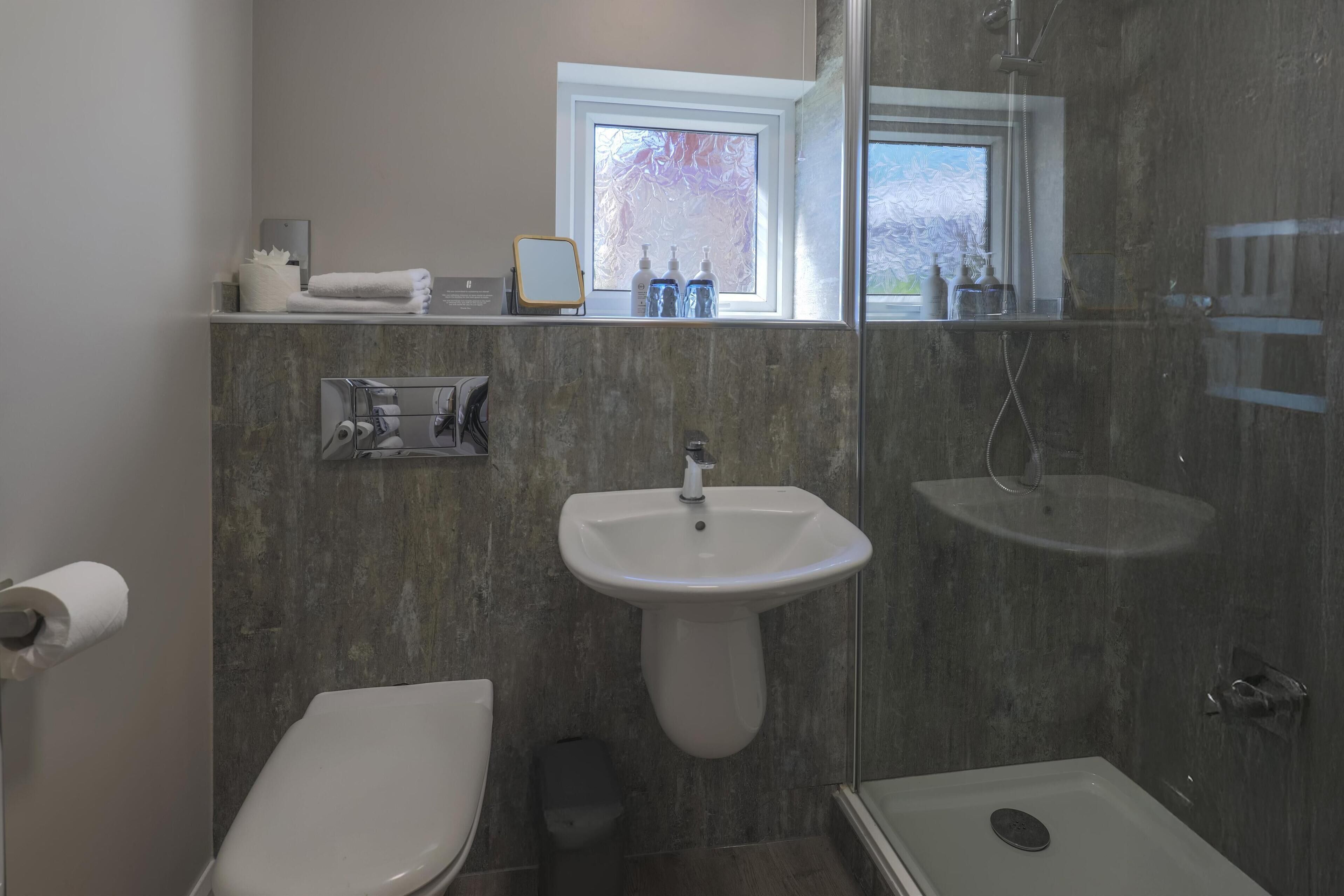 Une salle de bain équipée de toilettes, d’un lavabo et d’une douche.