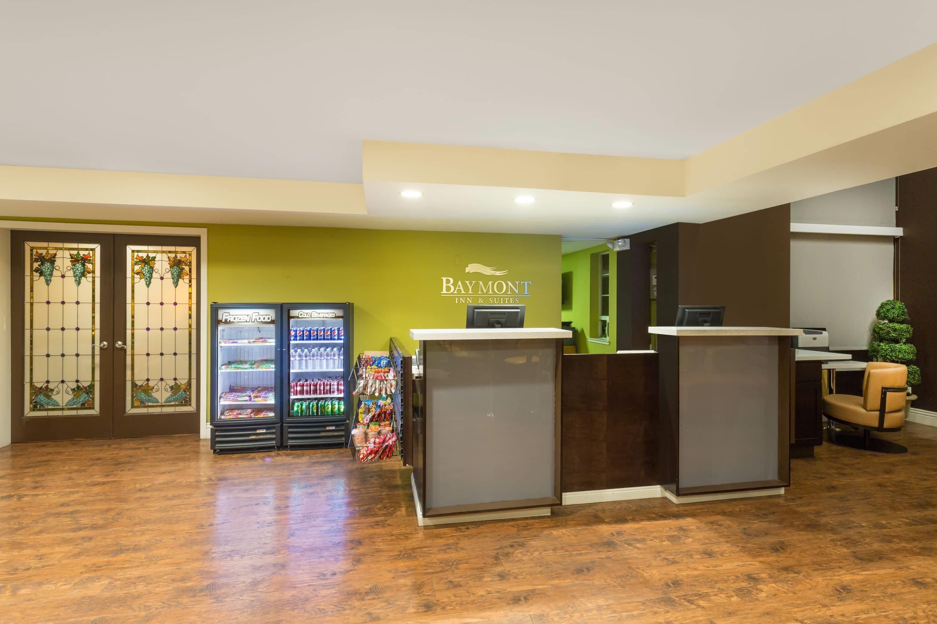 Ett receptionsområde med en receptionsdisk, en automater och en vägg med hotellets namn.
