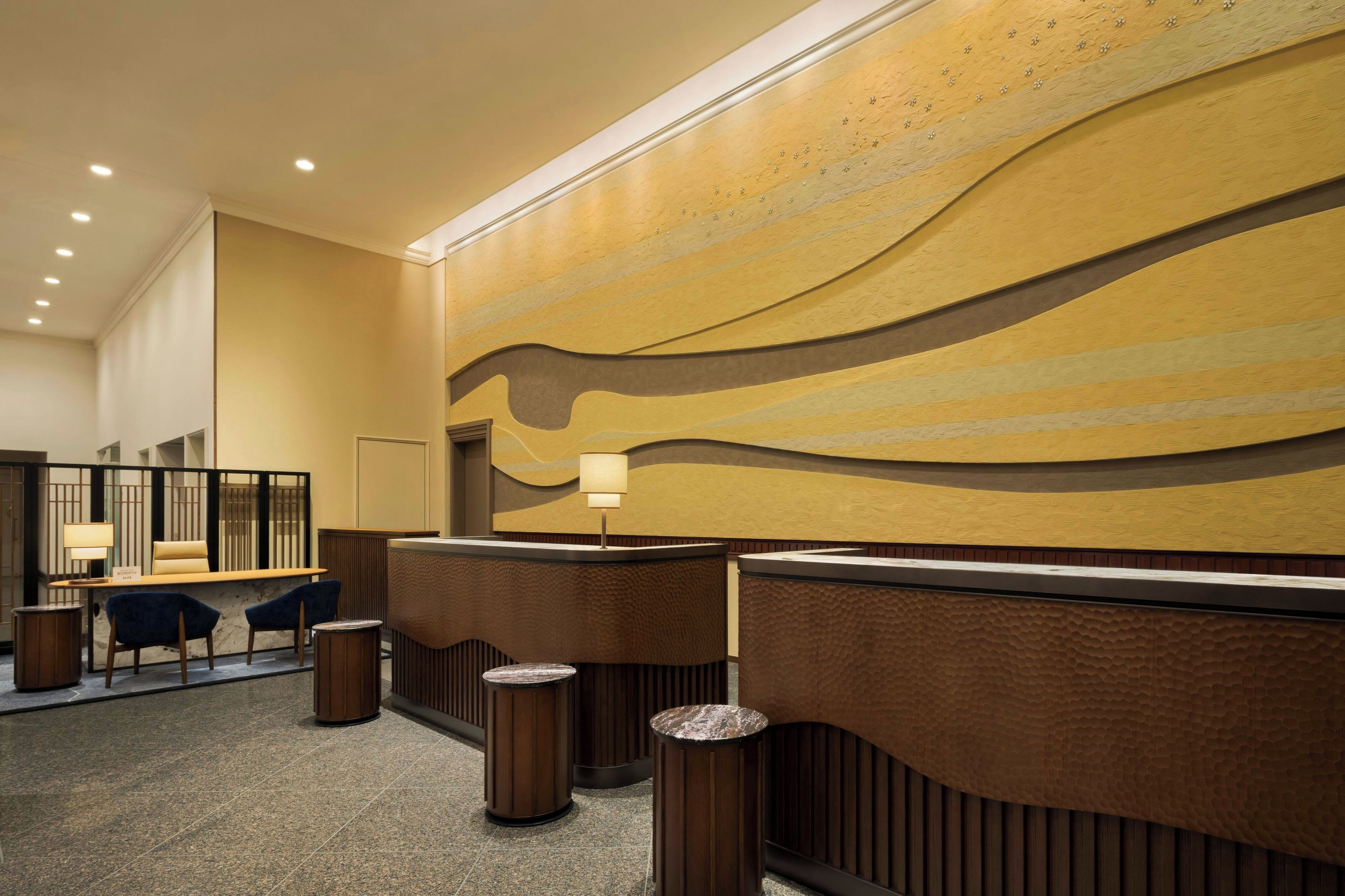 A hotel reception area with a modern design, featuring a reception desk, seating area, and a decorative wall.