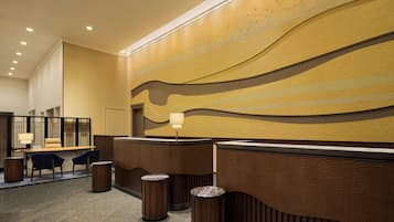 A hotel reception area with a modern design, featuring a reception desk, seating area, and a decorative wall.