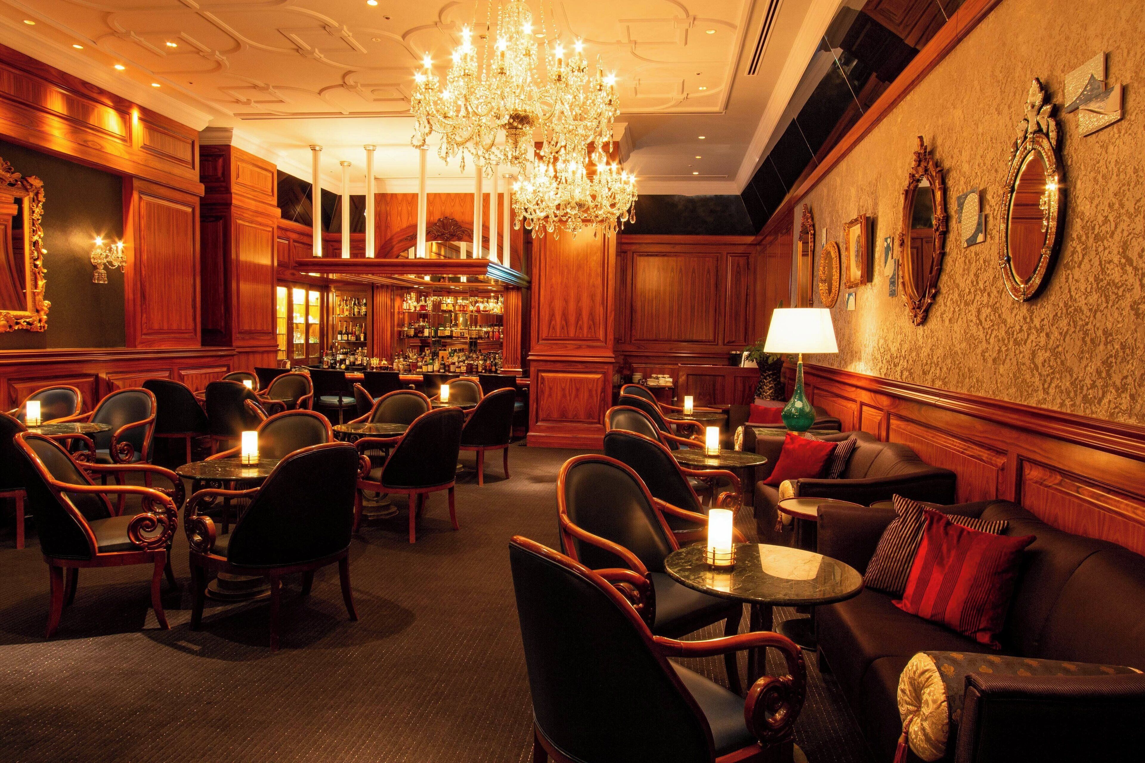 A bar area with multiple seating options, including tables and chairs, and a chandelier.