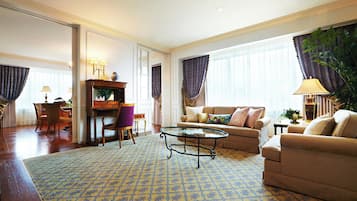 Un salón espacioso con alfombra estampada, un sofá, una mesa de centro y un comedor con sillas y una mesa.