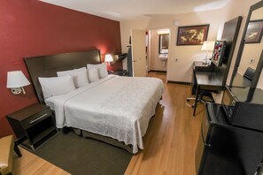 A hotel room with a bed, bedside table, lamp, desk, chair, and a mirror. - Red Roof Inn PLUS+ Ann Arbor - U of Michigan North (Ann Arbor)