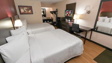 A hotel room with two beds, a desk, a television, a mirror, and a bathroom area.