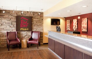Un área de recepción con pared de piedra, dos sillones de cuero, una mesa de madera, un mostrador de recepción y obras de arte en la pared.