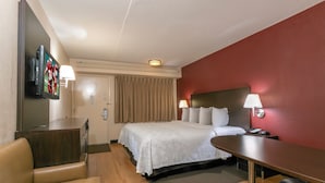 A hotel room with a bed, a desk, a chair, a television, and a lamp. - Red Roof Inn PLUS+ Ann Arbor - U of Michigan North (Ann Arbor)