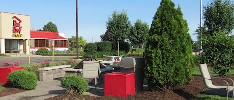 A Red Roof Plus store with a red roof and signage, surrounded by landscaped areas with bushes and a lawn.