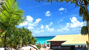 A resort with outdoor seating, palm trees, and a view of the ocean. - Barbados Beach Club Resort - All Inclusive (Maxwell)