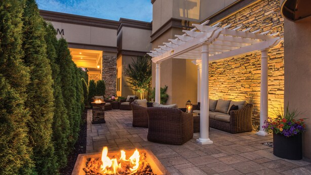 A patio area with a stone wall, outdoor furniture, and a fire feature.