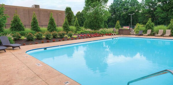 A swimming pool with lounge chairs and a 'No Lifeguard' sign.