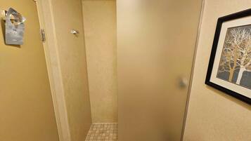 Une petite salle de bain avec une douche, des toilettes et un tableau encadré au mur.
