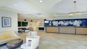 A spacious lobby with a reception desk, seating area, and a modern chandelier.