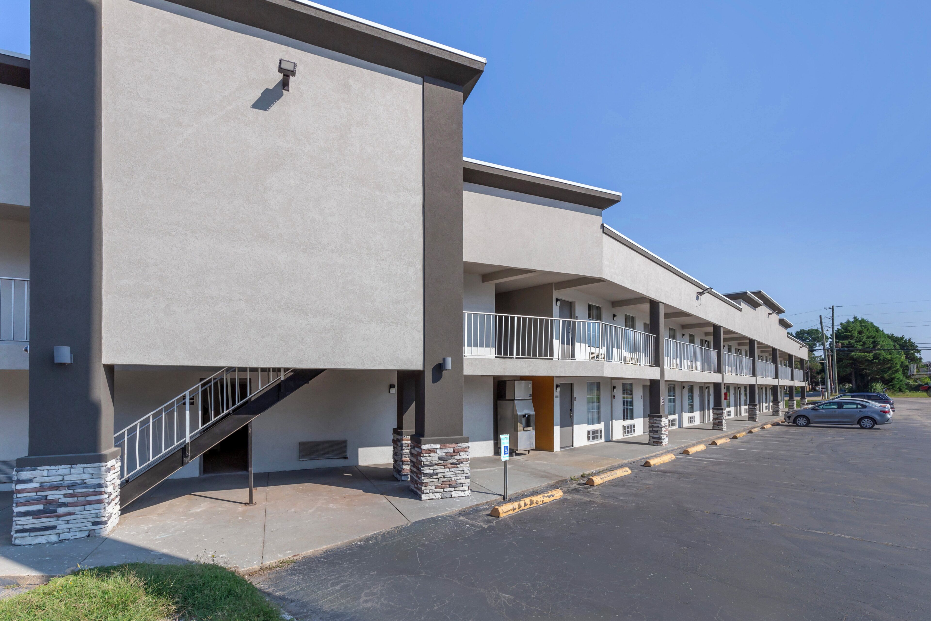 Um hotel moderno de vários andares, com escadaria central, varandas e estacionamento.