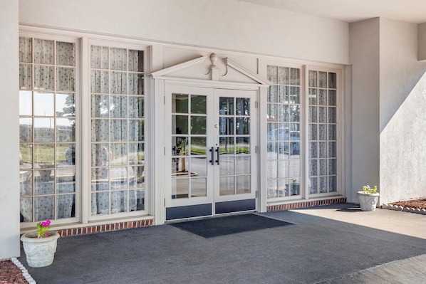 A building entrance with a double door, large windows, and a small potted plant.