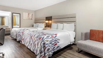 A hotel room with a large bed, a desk, a chair, and a nightstand.
