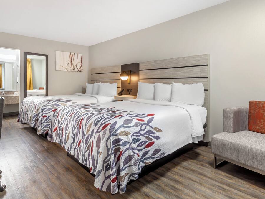 A hotel room with a large bed, a desk, a chair, and a nightstand.