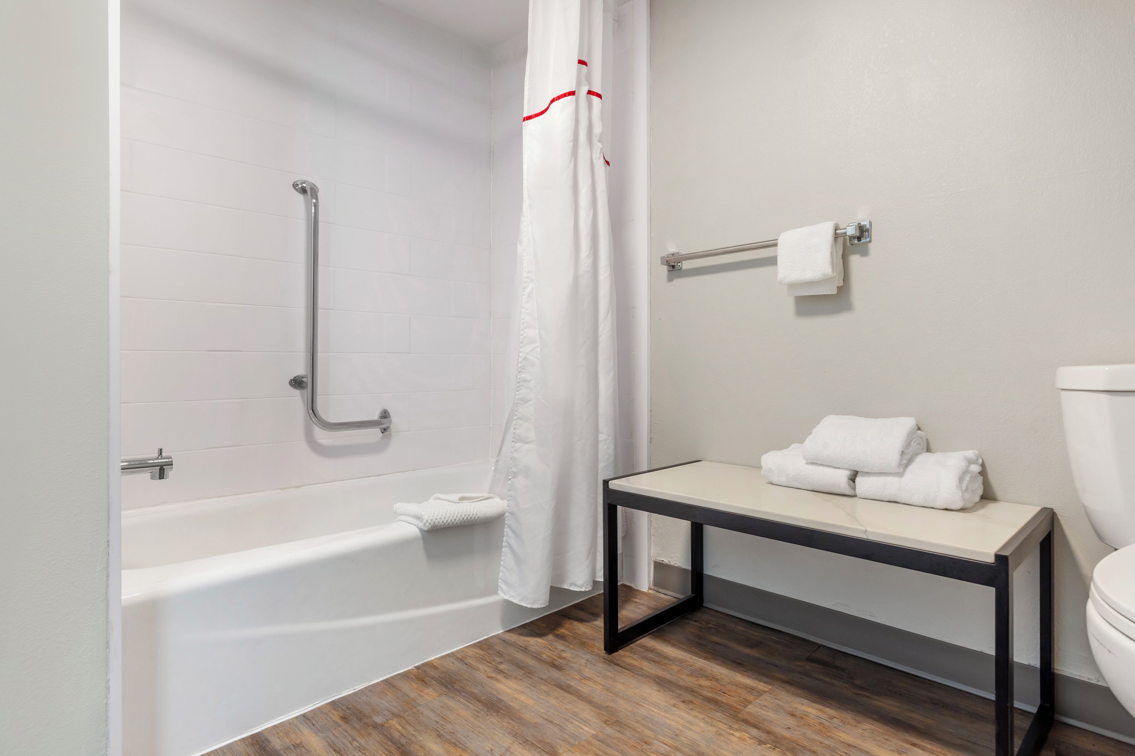 A bathroom with a bathtub, a toilet, and a small table with towels.