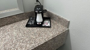 Una cafetera sobre una encimera de granito con un enchufe de corriente al fondo.