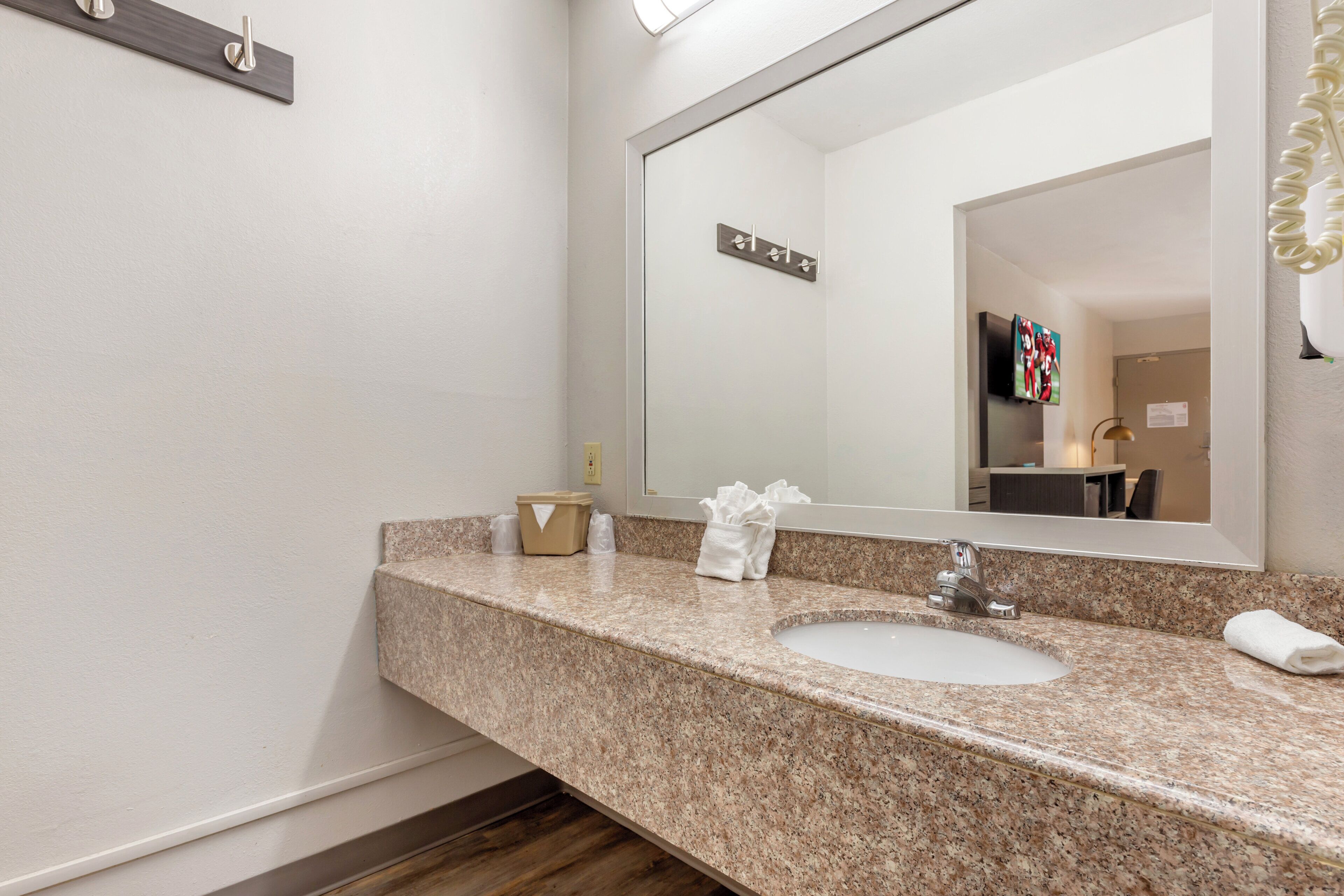 Une salle de bain avec un comptoir en granit, deux lavabos, un grand miroir et un porte-serviettes.