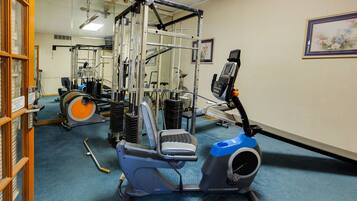 A gym with exercise equipment including a stationary bike, a treadmill, and a weight machine.