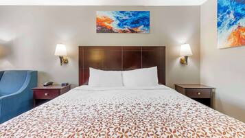 A hotel room with a large bed, two bedside tables, a chair, and two wall-mounted lamps.