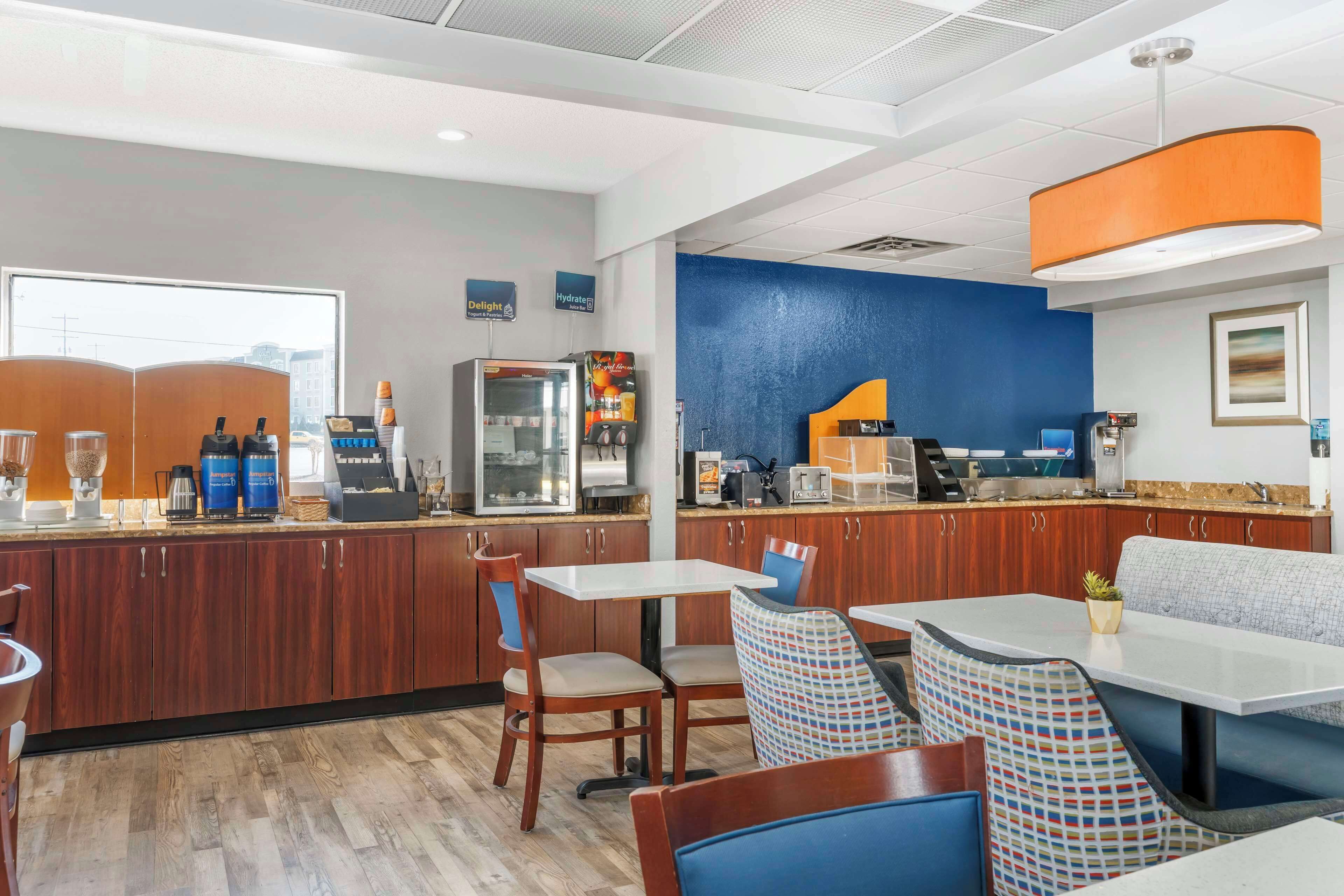 Un restaurante de hotel moderno con armarios de madera, una estación de café y zonas de estar.