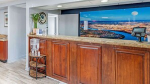 A reception area with a wooden counter, a large cityscape mural, a water dispenser, and a clock on the wall. - Best Western Royal Inn (Chattanooga)