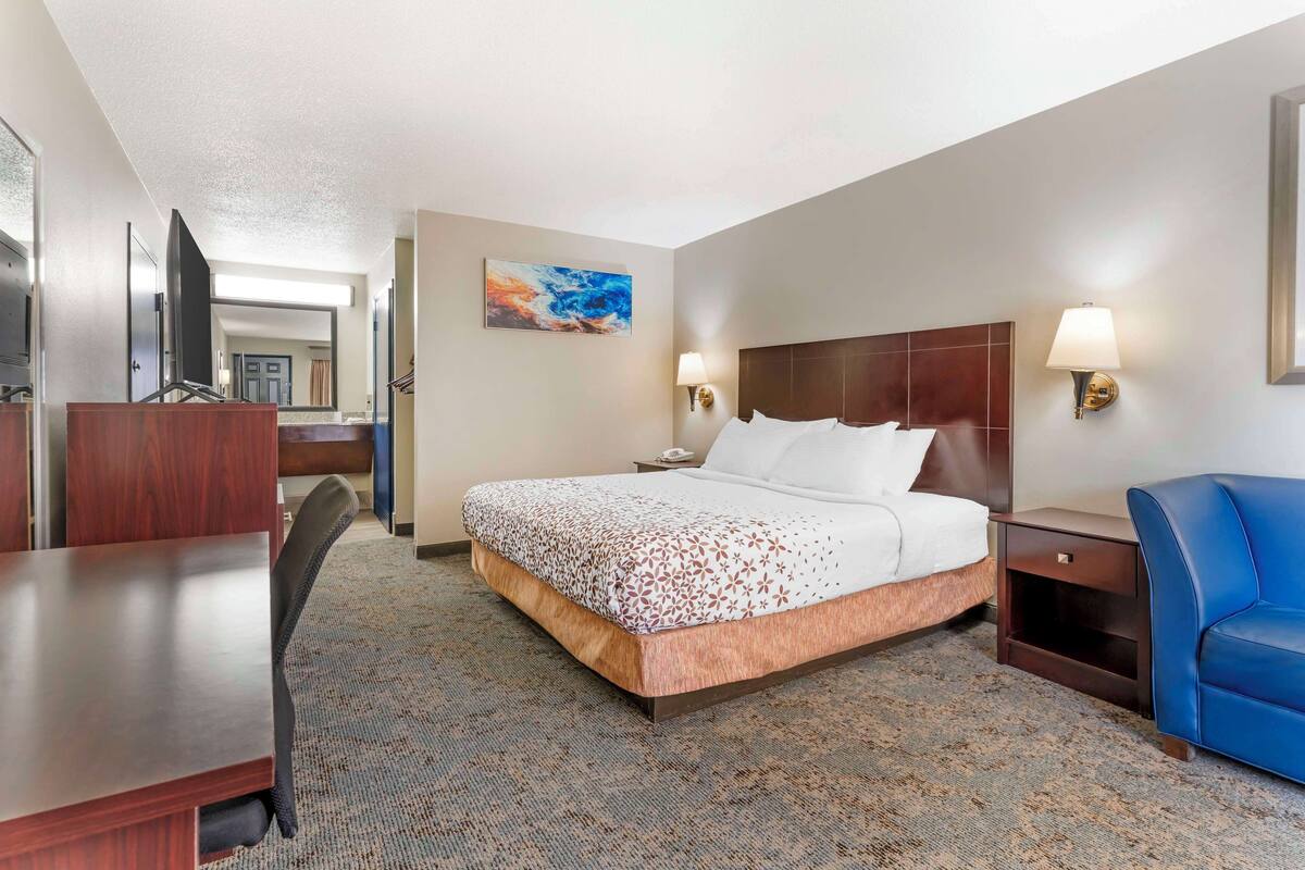 A hotel room with a bed, desk, chair, and a blue sofa.