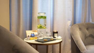 A room with a round table featuring a candle, a glass jar with a plant, and a tray with cookies.