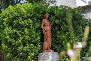 A statue of a woman in a garden setting.