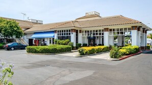 A hotel with a tiled roof, a blue awning, and a 'Welcome' sign.