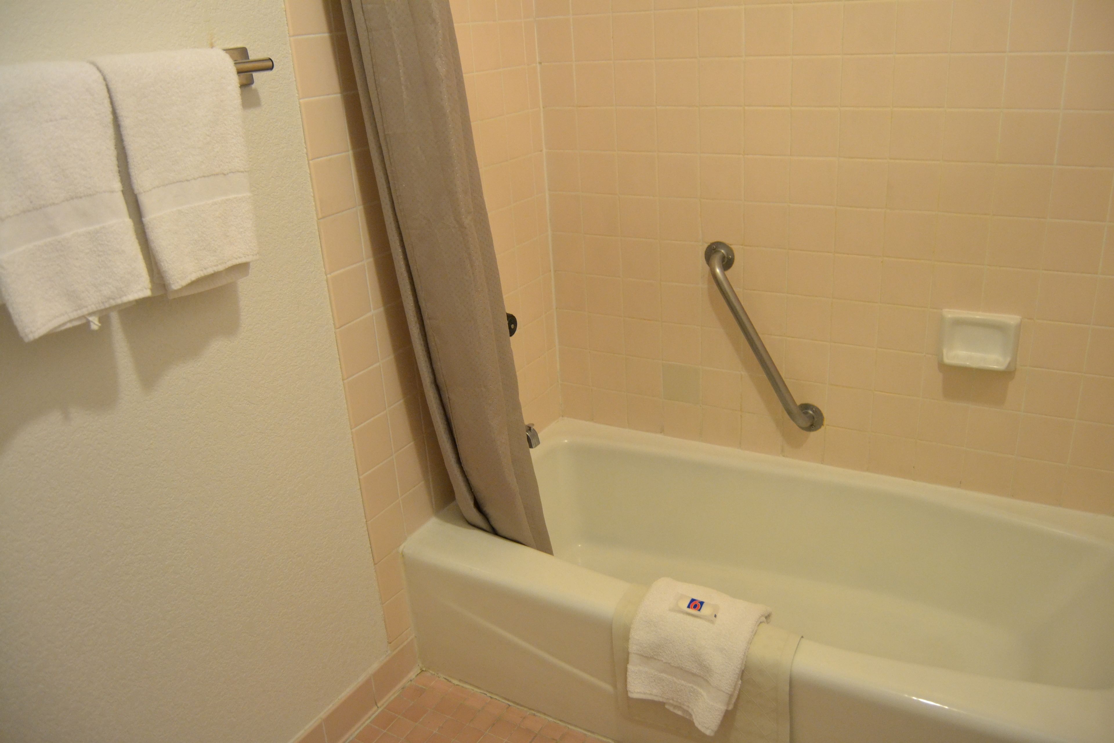 Une salle de bain équipée d’une baignoire, d’un rideau de douche et d’une barre d’appui.