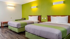 A hotel room with two beds, a small table, and a chair.