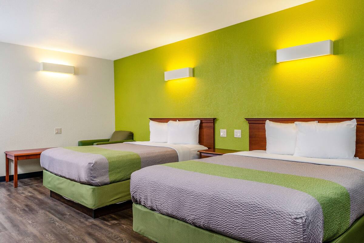 A hotel room with two beds, a small table, and a chair.