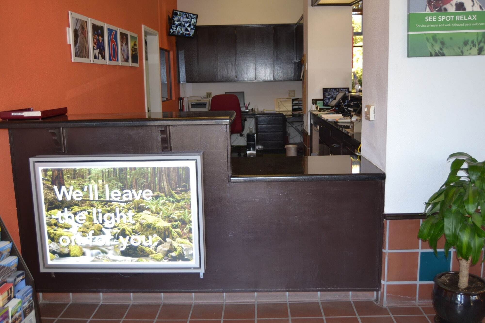 A reception desk with a large poster advertising a light left for guests.