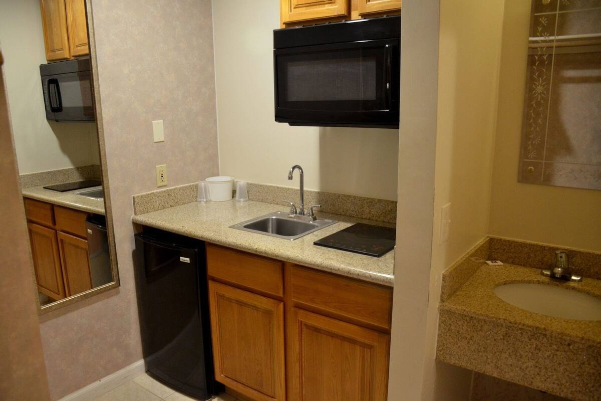 A compact kitchen with a dishwasher, a sink, a microwave, and wooden cabinets.