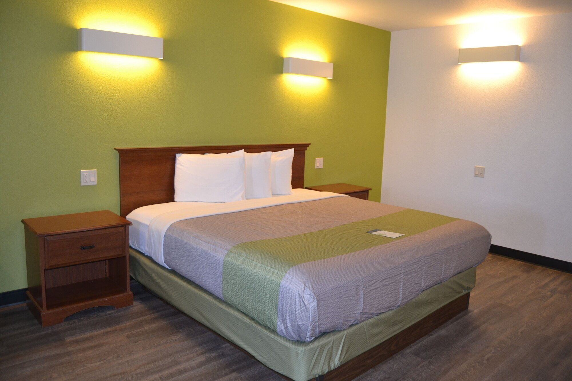 A hotel room with a bed, two bedside tables, and two wall-mounted lights.