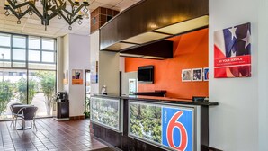 A hotel reception area with a modern design, including a reception desk, a large window, and a view of the outdoors.