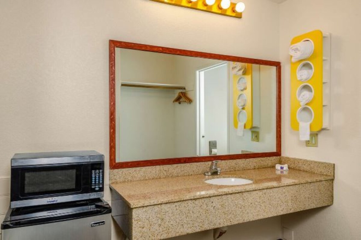 Une salle de bain équipée d’un lavabo, d’un miroir et d’un four à micro-ondes.