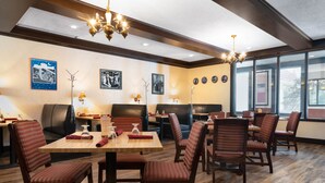 Un comedor con mesas y sillas de madera, candelabros y cuadros en las paredes.