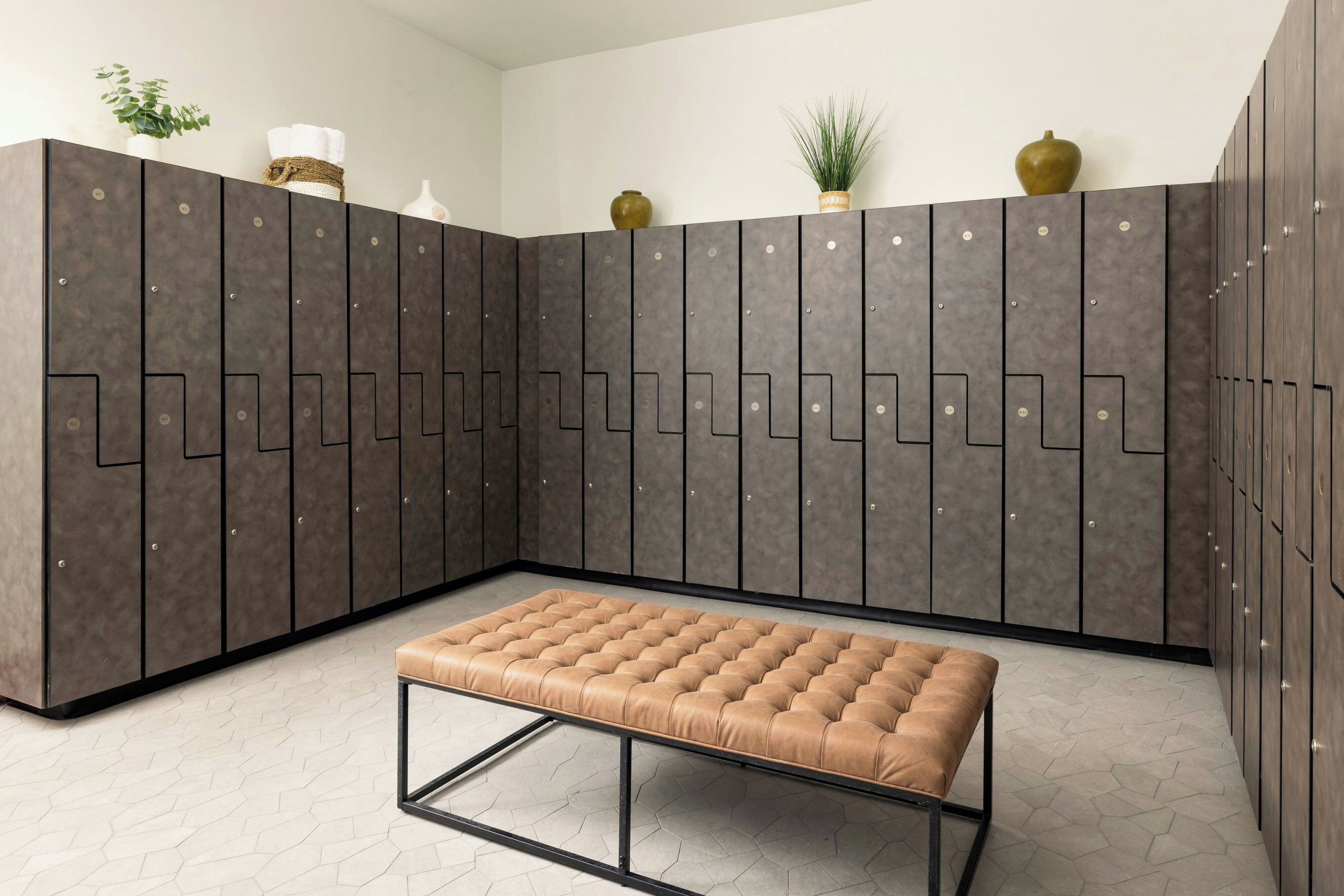 Une chambre moderne avec une grande armoire, un banc rembourré et des objets décoratifs accrochés au mur.