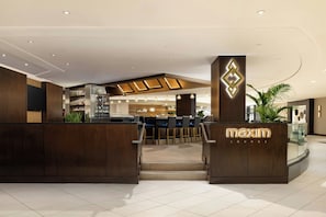 A modern lounge area with a reception desk, seating, and a bar.