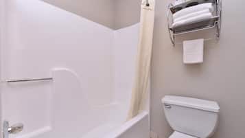 A bathroom with a bathtub, toilet, and a towel rack with towels.