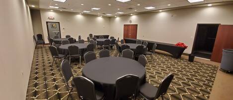 A conference room with multiple tables and chairs, carpeted floor, and a door marked "EXIT".